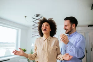 A imagem mostra um casal feliz ao entrar na casa nova; Foto para ilustrar o texto sobre a vistoria imobiliária na experiência do cliente