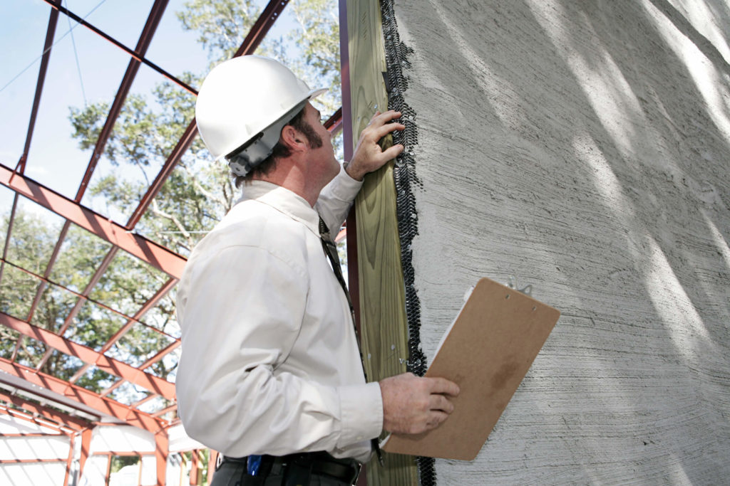 A imagem mostra um homem observando detalhes de uma parede. Foto para ilustrar o texto sobre manutenção preventiva
