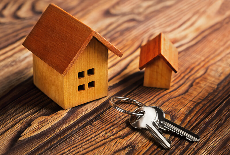 A imagem mostra duas casas pequenas de madeira uma chave. Foto para ilustrar o texto sobre alugar sem fiador
