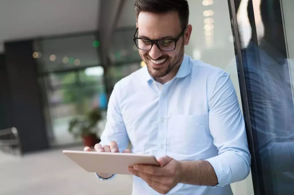 A imagem mostra um homem de meia idade sorrindo e mexendo em um tablet. Foto para ilustrar o texto sobre vistoria de imóvel