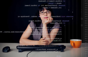 A imagem mostra a foto de uma mulher com vários códigos de computação na sua frente. Foto para ilustrar o artigo sobre as mulheres na tecnologia